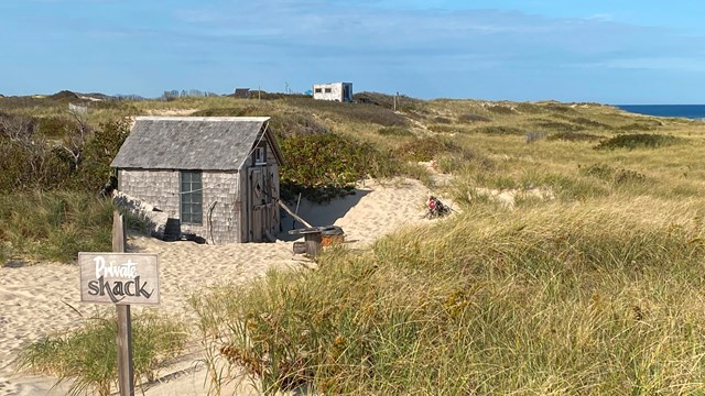 A small wooden shack nestled amongst sand dunes.